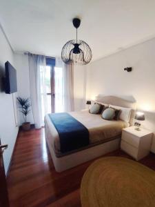 a bedroom with a large bed and a chandelier at Pura Vida Apartmento in Ramales de la Victoria +7 photos