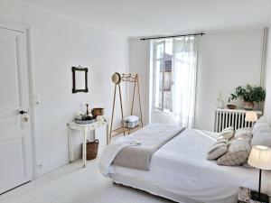 a white bedroom with a bed and a window at La Maison Ânanda in Aigre