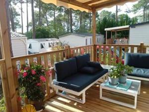 eine Veranda mit einem Stuhl und einem Sofa auf einer Terrasse in der Unterkunft CAMPING Les EMBRUNS - 4 ETOILES in Lège-Cap-Ferret
