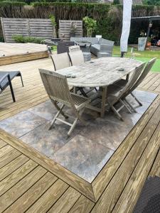 une table et des chaises en bois sur une terrasse en bois dans l'établissement 3 chambres 24 heures, à Mulsanne