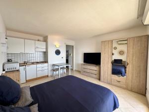 a bedroom with a blue bed and a kitchen at Studio vue mer limitrophe à Monaco in Roquebrune-Cap-Martin