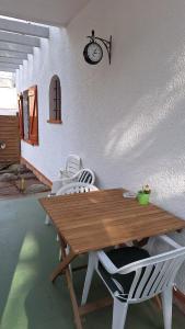 ein Holztisch mit weißen Stühlen und eine Uhr an der Wand in der Unterkunft La Garsa in Aiguafreda