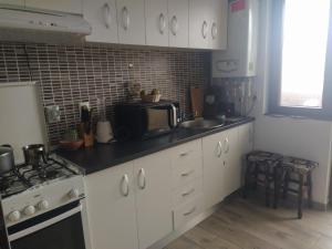 une cuisine avec des armoires blanches, un évier et un micro-ondes dans l'établissement Escapadă în Iași - Apartament spațios cu balcon și parcare, à Iaşi