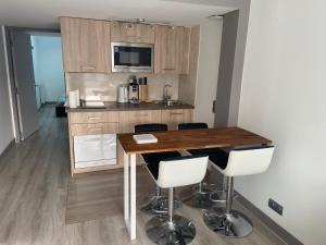 a kitchen with a wooden table and white chairs at Appartement entier proche du tramway in Carbon-Blanc