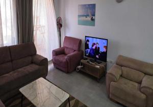 a living room with two couches and a flat screen tv at شاليه إطلالة مميزة in El Alamein
