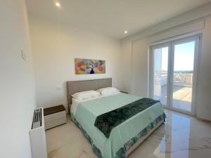 a white bedroom with a bed and a large window at Rooftop Galatina in Galatina