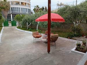 a table and two chairs under a red umbrella at Arta room in Durrës +1 photo