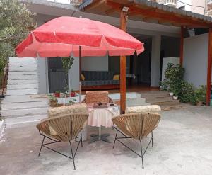 a table and two chairs with a red umbrella at Arta room in Durrës