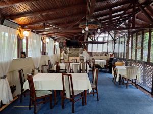 a dining room with white tables and chairs at Clubul Veteranilor in Viforîta