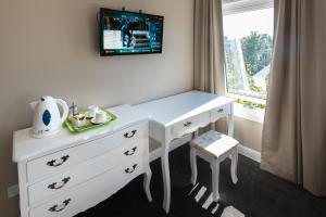 een wit bureau met een tv aan de muur bij Lily Sands Inn in Melbourne