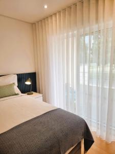 a bedroom with a bed and a large window at Barra B Suite Apartment - 4min walk from BEACH, Terrace in Praia da Barra
