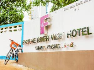 una bicicletta parcheggiata di fronte a un edificio con un cartello di Fortune Riverview Hotel Chiang Khong a Chiang Khong
