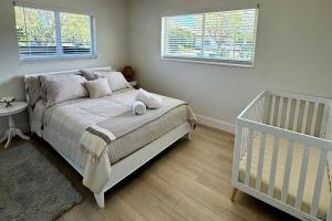 a bedroom with a bed and a crib and two windows at Chic-ness Oasis in Cutler Bay +35 photos