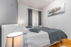a white bedroom with a bed and a stool at Floyd in Bibinje