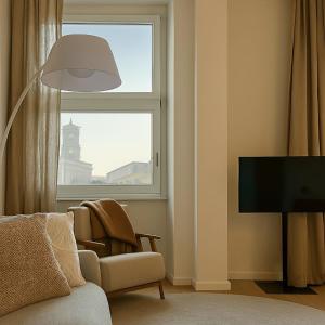 a living room with a tv and a chair and a window at Giselda Suite - Oval in Turin