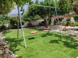 two swings in a yard with green grass at Konstantina's cottage Ideal BaseforBalos & Elafonisi in Kissamos