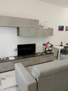 Una sala de estar con un sofá y un televisor. en Topazio blu, en Alghero