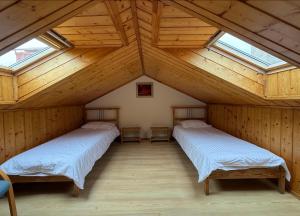 two beds in a wooden room with skylights at Apartamentai Nidoje su vaizdu į marias in Nida