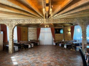 a large room with wooden ceilings and tables and chairs at Woodville Resort in Moisei