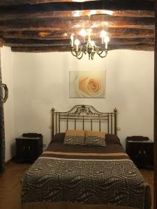 ein Schlafzimmer mit einem Bett und einem Kronleuchter in der Unterkunft Casa Rural Arco Antico in Navahermosa
