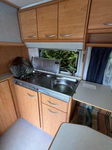 a kitchen with a stove and a sink in an rv at Vintage przyczepa JustarniaCamp in Jastarnia +5 photos