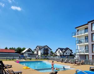a person standing in a swimming pool next to a building at MB Apartments z Basenem i Ogrodem in Sarbinowo +23 photos