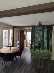 een woonkamer met een tafel en een muurschildering van een hert bij Bungalow in het bos in Nunspeet +5 foto's