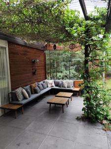 een terras met een bank en tafels in een gebouw bij Bungalow in het bos in Nunspeet