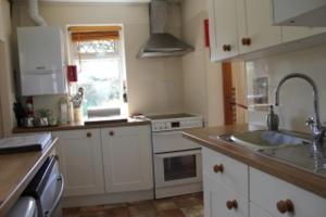 una cocina con armarios blancos y fregadero en Parrs cottage en Wollaston
