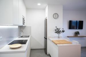 a white kitchen with a sink and a clock on the wall at ABLANCAS - La Restinga in La Restinga