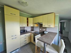 a kitchen with yellow cabinets and a table with chairs at Apartments VillaMare in Grebaštica