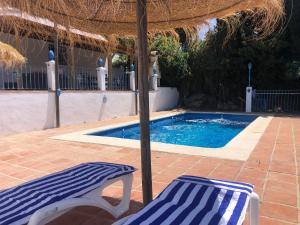 una piscina con sombrilla y dos tumbonas en Villa vistas al lago with private pool, en Viñuela