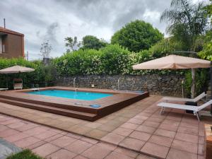 a swimming pool with a table and an umbrella at Villa Luigi in Valverde