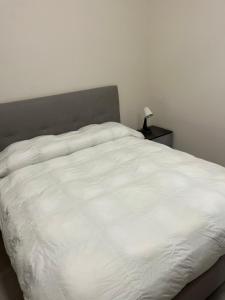 een wit bed in een slaapkamer met een nachtkastje bij Little House On The Sea in Acireale +9 foto's