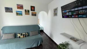 ein Wohnzimmer mit einem blauen Sofa und einem Flachbild-TV in der Unterkunft Casa Mango, con piscina y vistas al mar y volcán in El Paso