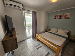 een slaapkamer met een bed, een televisie en een balkon bij Apartments VillaMare in Grebaštica