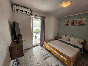 a bedroom with a bed and a television and a window at Apartments VillaMare in Grebaštica