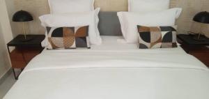 a bed with white sheets and pillows on it at Aksil Jaam in Dakar