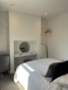 een slaapkamer met een wit bed en een spiegel bij The Nest at Amble in Amble