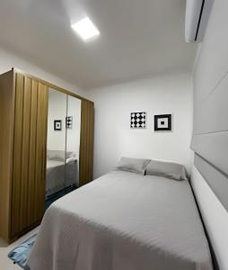 een slaapkamer met een groot bed en een spiegel bij Casa moderna no Jardim Italia in Maringá