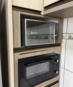een magnetron boven een oven in een keuken bij Casa moderna no Jardim Italia in Maringá