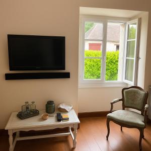 a living room with a tv and a chair and a coffee table at Grande maison familiale avec jardin- 10 pers au coeur du Bearn in Guinarthe-Parenties