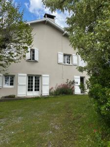 a white house with white windows and a yard at Grande maison familiale avec jardin- 10 pers au coeur du Bearn in Guinarthe-Parenties