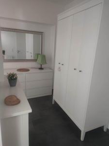 a white kitchen with white cabinets and a table at Wohnen bei frau tinz - Studio - Bahnhof- und Zentrumsnähe in Neunkirchen
