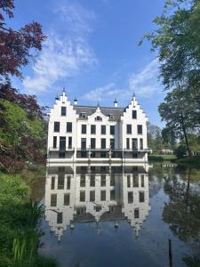 a large white house with its reflection in the water at Heerlijk chalet midden in de natuur in Putten