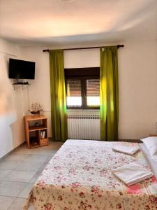 a bedroom with a bed with green curtains and a television at Ruža i Natalija in Karlobag