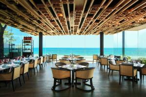 a restaurant with tables and chairs and a view of the ocean at Hua Hin Marriott Resort and Spa in Hua Hin