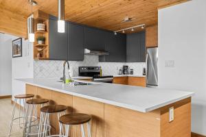 a kitchen with black cabinets and bar stools at Alps #201- LEED Gold Certified & Dog Friendly in Canmore