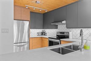 a kitchen with stainless steel appliances and wooden cabinets at Pyrenees #202 - LEED Gold Certified in Canmore +57 photos