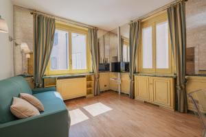 a living room with a blue couch and some windows at Elegant apartment inside the Roman Forum in Rome